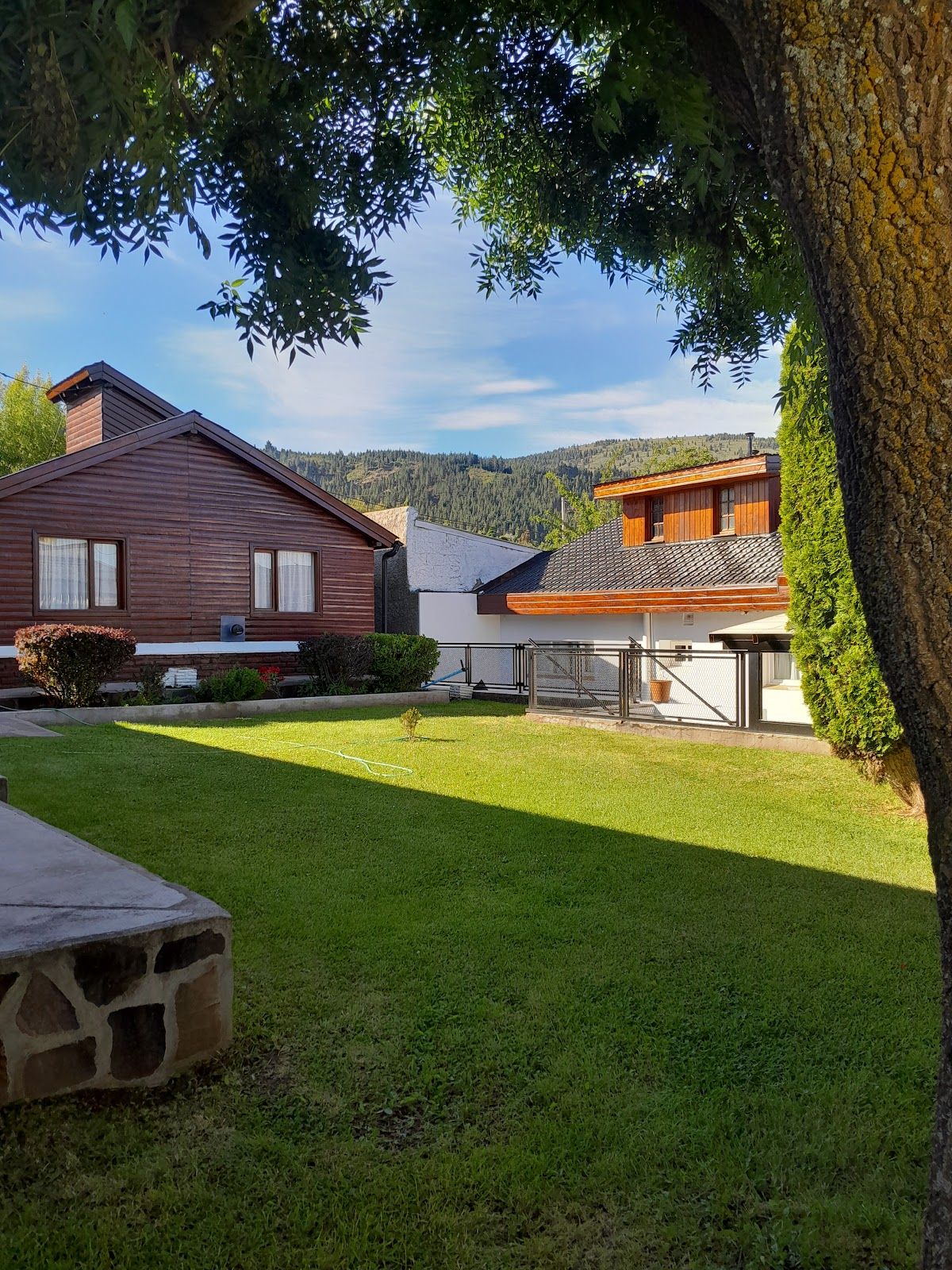 Cabañas de madera de Cerro la Zeta entre el parque verde, con el cerro boscoso de fondo