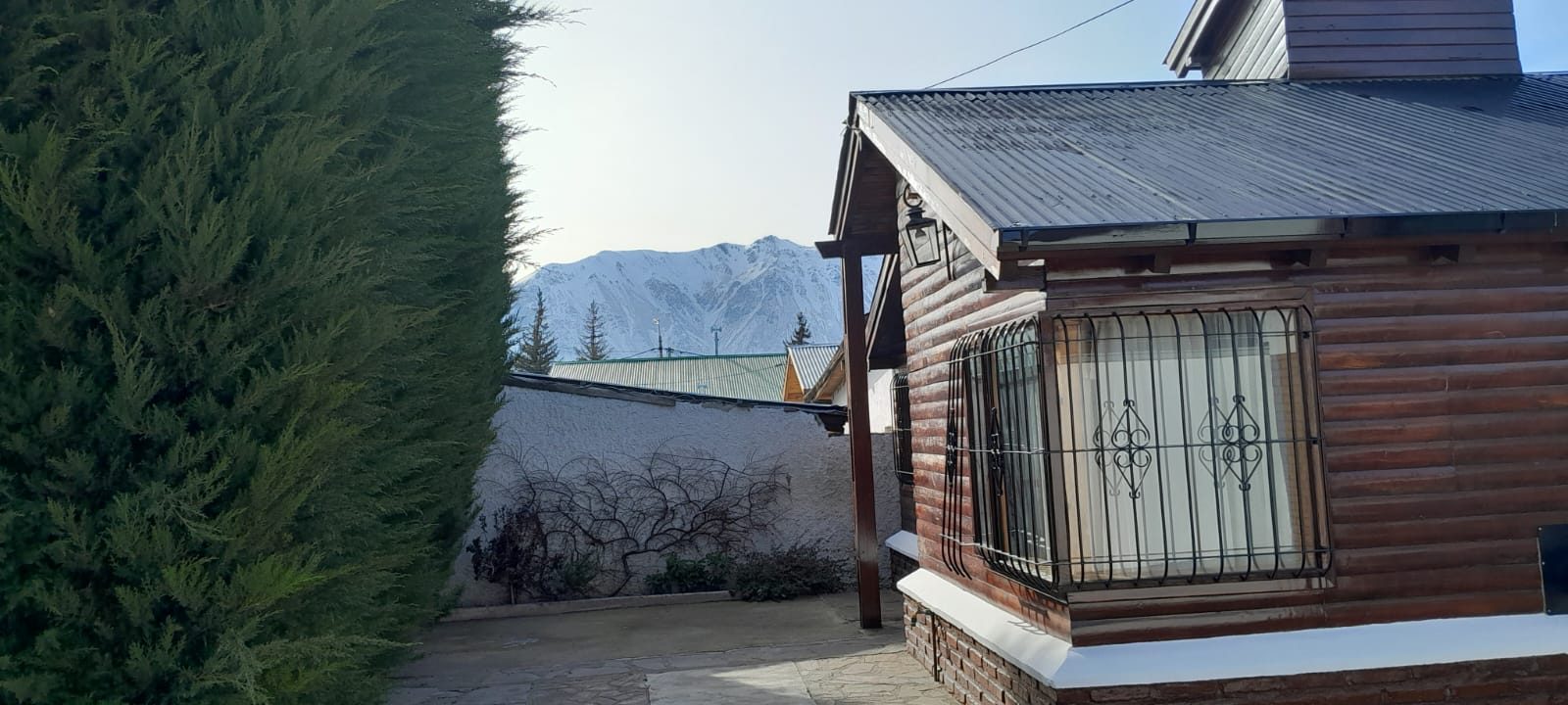 Una de las cabañas junto al cerco de cipreses, con el cerro nevado asomando de fondo