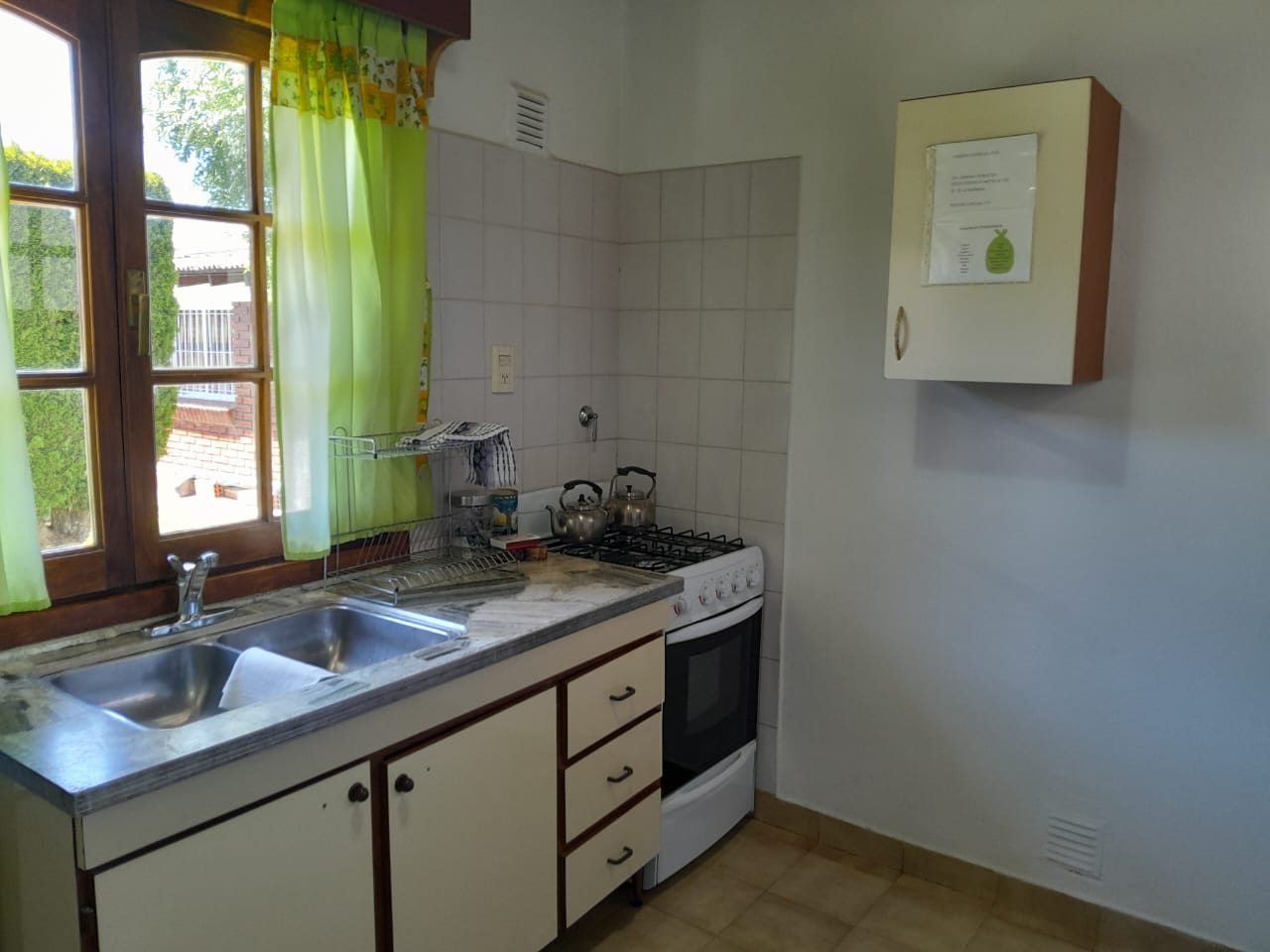 Cocina con bacha doble y ventana al parque, con la cortina verde corrida
