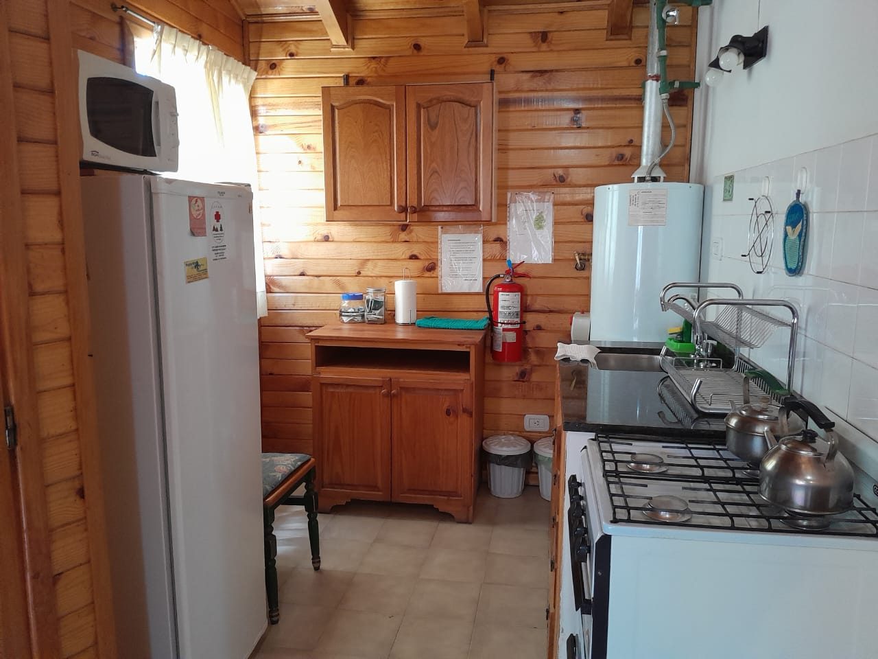 Cocina equipada con heladera, microondas y alacenas de madera