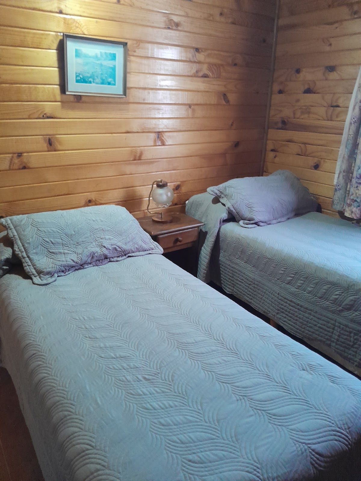 Dormitorio con dos camas individuales y paredes de madera, prolijo y cálido