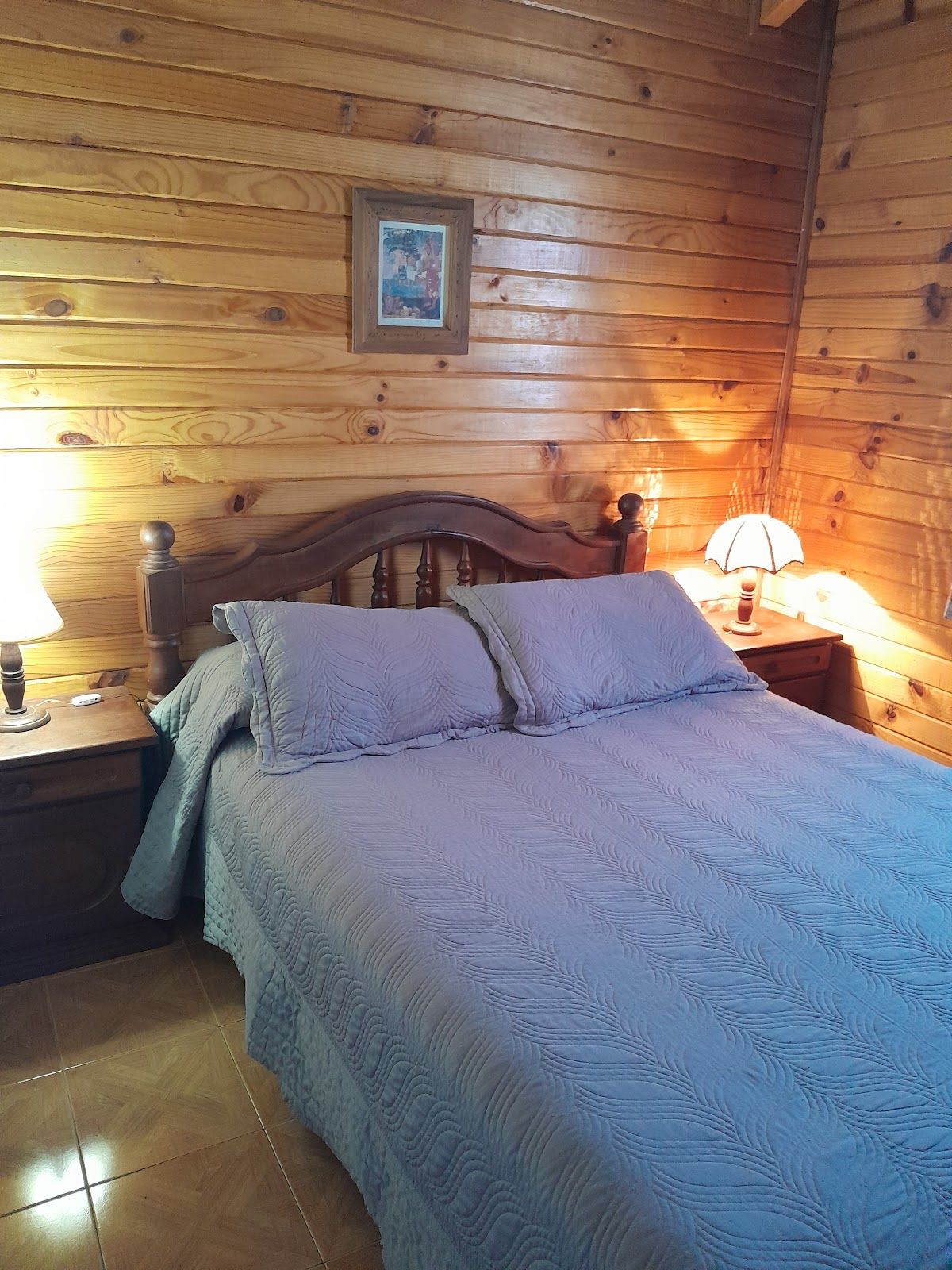 Dormitorio matrimonial con paredes de pino, luz cálida y ropa de cama lista