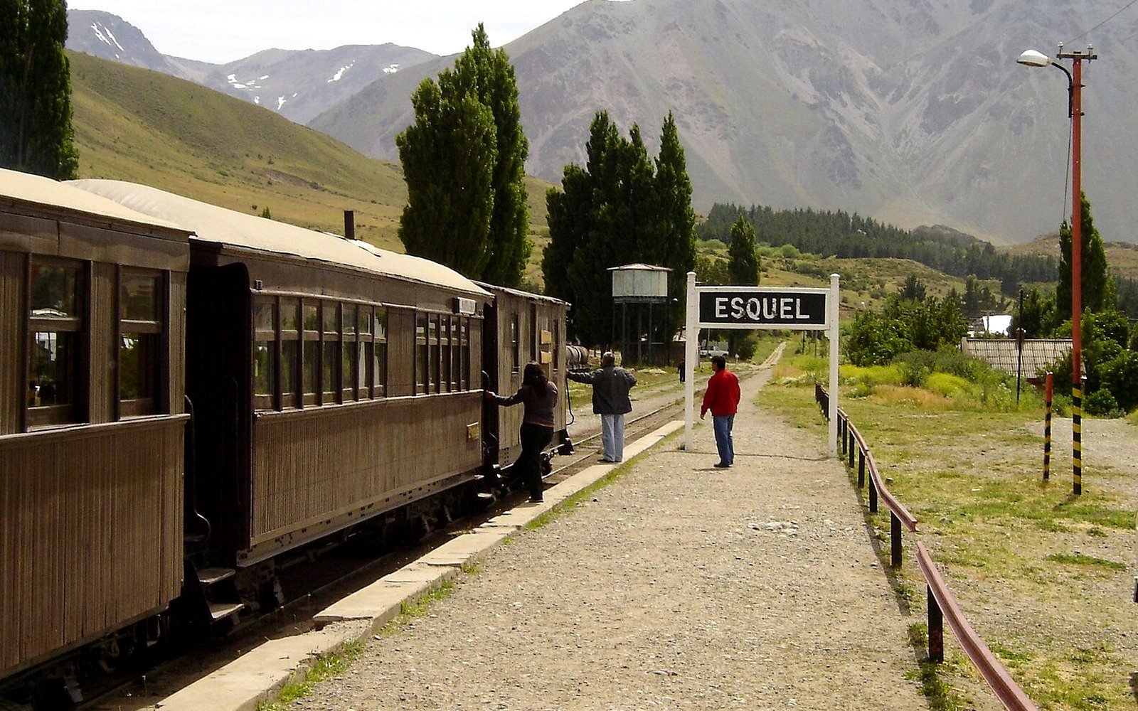 La Trochita en la estación de Esquel: los vagones de madera, el cartel de la estación y los cerros de fondo