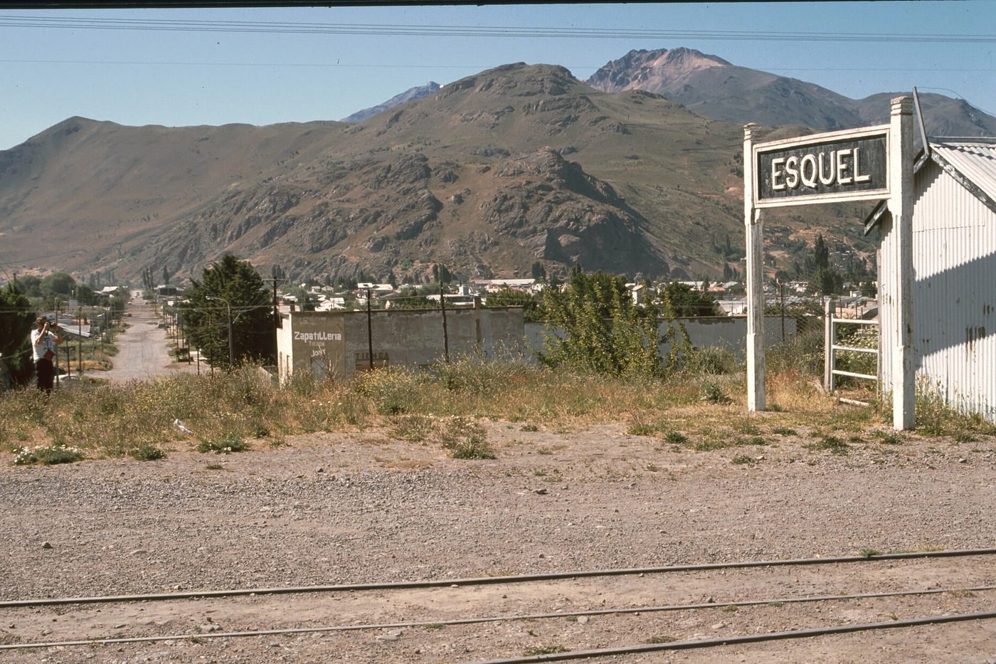 El cartel de la estación de Esquel, con el pueblo y el cerro detrás