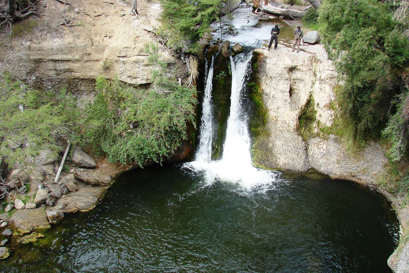Un salto de agua cayendo entre las rocas y la vegetación del valle, cerca de Trevelin